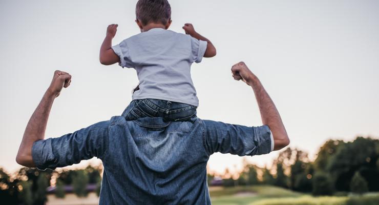 Un père porte son enfant sur les épaules, tous deux montrent leurs muscles comme symbole de résistance et de vitalité