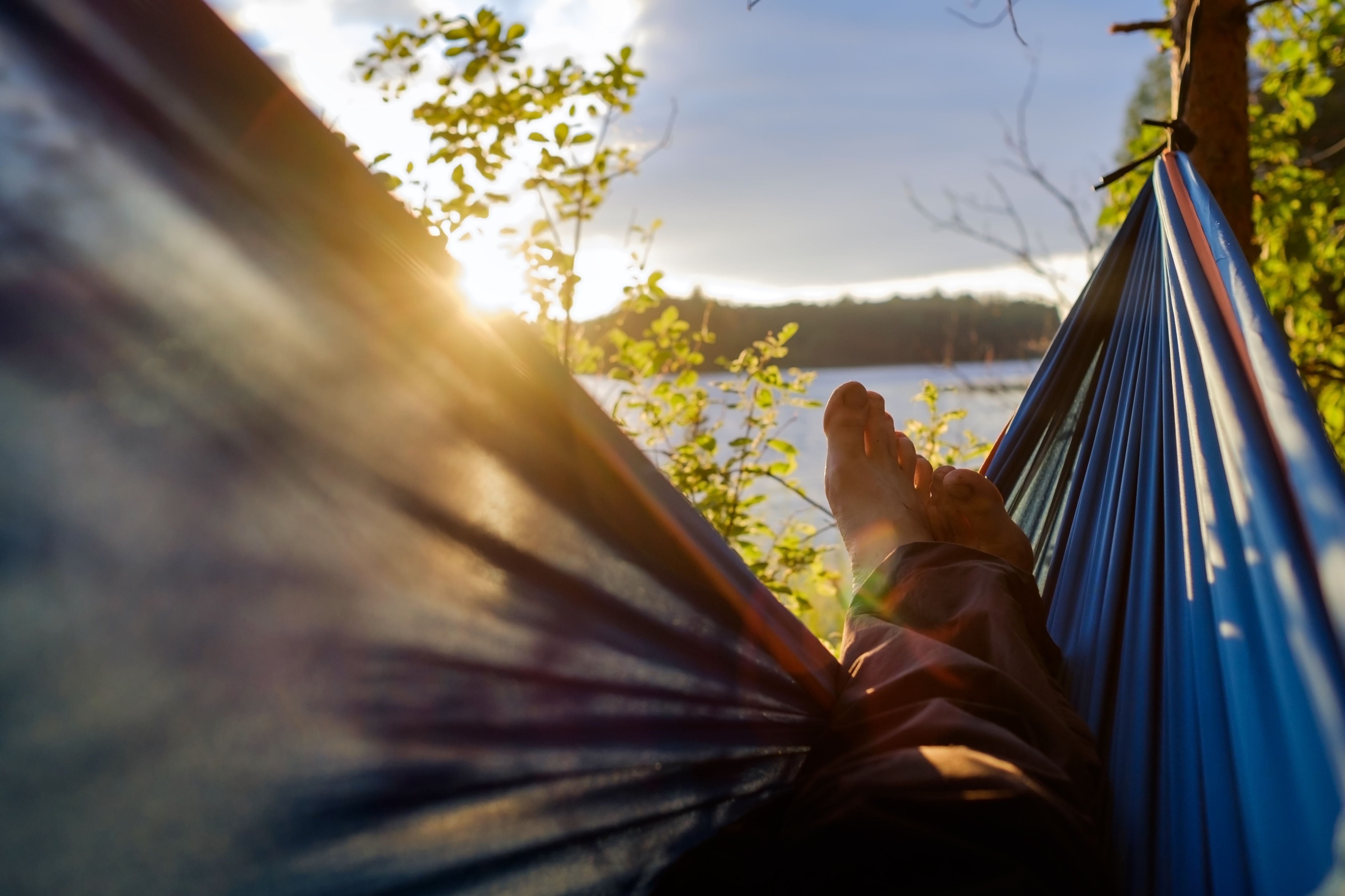 Personne détendue dans un hamac au coucher du soleil, symbole de repos naturel et de sérénité