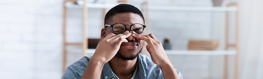 Homme souffrant de fatigue oculaire et de sécheresse des yeux devant un écran