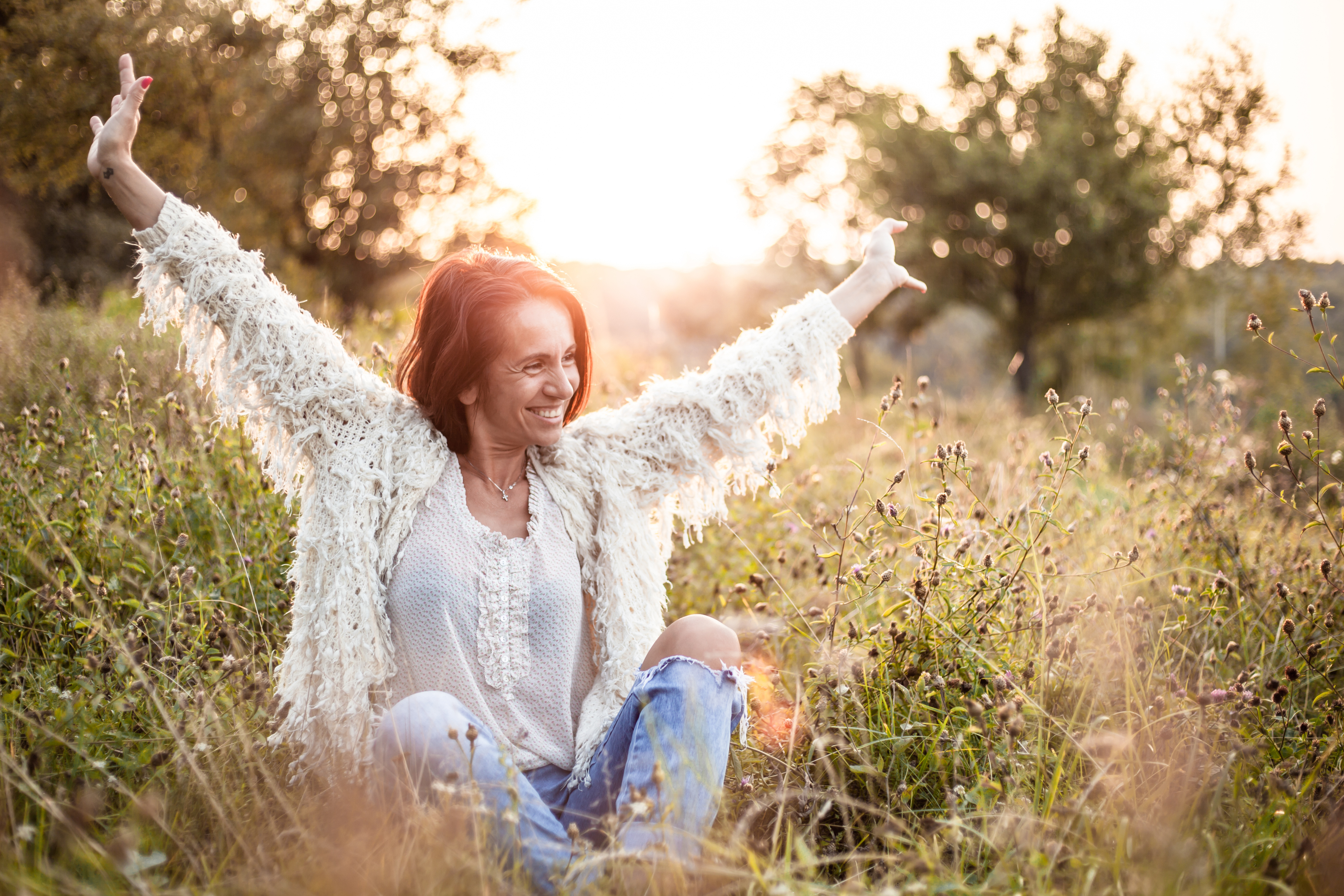 Vrouw van middelbare leeftijd in de natuur met open armen – thema menopauze en balans